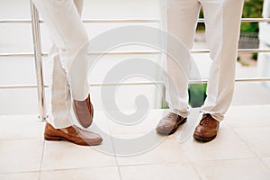 The legs of two men standing on the balcony, close-up. The groom and his best man during the preparation for the wedding