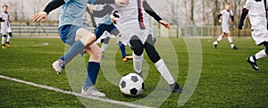 Legs of two young football players on a match. Two soccer players running and kicking a soccer ball