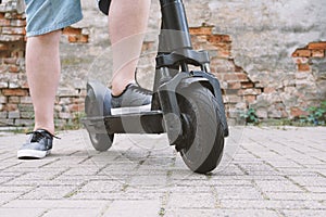 Legs of unrecognizable man with electric kick scooter or e-scooter