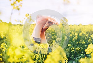 Legs up of happy female lying in deep yellow flowers meadow. Happiness in nature concept image