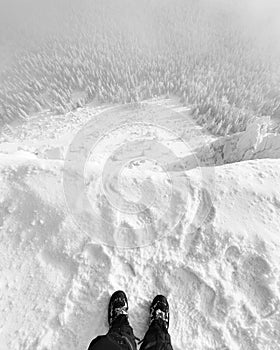 Legs and a view from the cliff to the forest in winter