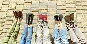 Legs view of friends relaxing and chilling outdoor - Young people having fun together outside in historical old town center-