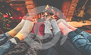 Legs view of happy family lying down next fire place wearing warm wool socks - Winter, holiday, love and cozy concept - Focus on