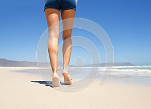 Legs walking barefoot on beach