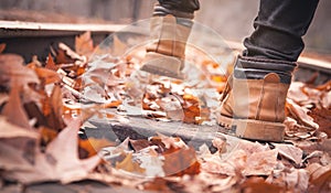 Legs of a woman in brown boots in autumn park