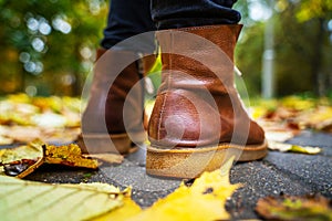 Legs of a woman in brown boots walking in a park