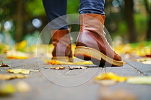 Legs of a woman in brown boots walking in a park