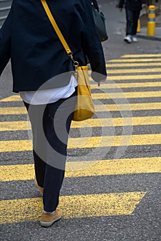 Legs of woman crossing the street on yellow zebra