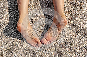 Legs of a woman lying on the sand of a beach.