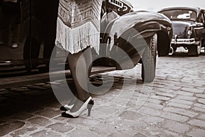 Legs of woman near old auto. Young woman in high heels shoes