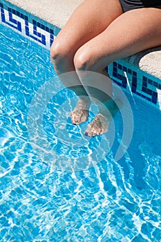 Legs of woman sitting on curb pool