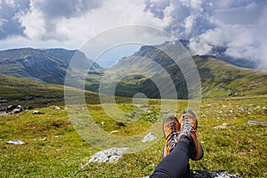 Legs of a woman sitting on the grass in the mountains