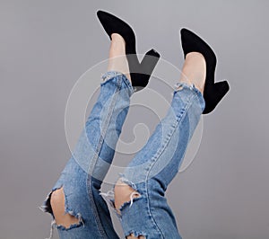 Legs of woman in stylish high shoes, on gray background