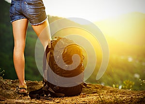 Legs of a woman tourist and travel backpack on a mountain top