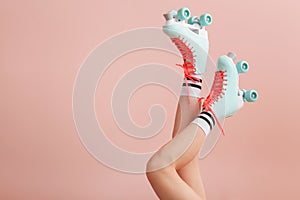 Legs of woman in vintage roller skates on color background