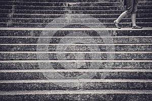 Legs of a woman walking between concrete stairs