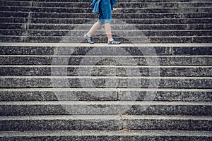 Legs of a woman walking between concrete stairs