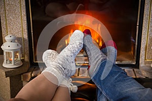 Legs in woolen socks stretched out heat up near fireplace