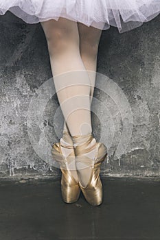 Legs of the young ballerina with pointe shoes by the grunge wall