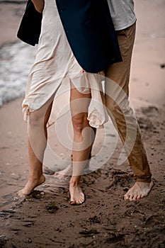 Legs of a young couple of a husband and wife stand on wet sand