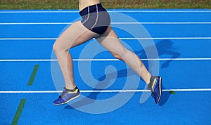 Legs of young female runner running on athletic track