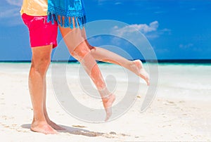 Legs of young hugging couple on tropical turquoise beach