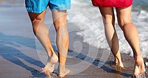 Legs of young married couple are walking along sea along beach