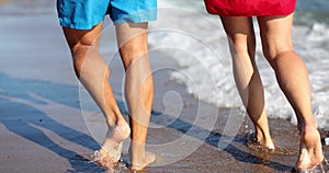 Legs of young married couple are walking along sea along beach