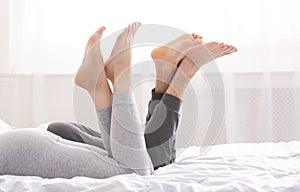 Legs of young playful couple lying in bed together