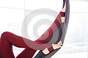 Legs of young woman in leggins using hammock at studio