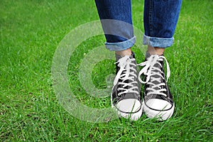 Legs of young woman standing on green grass in park