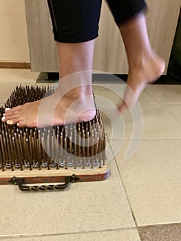 Legs of a young yoga girl stand on sharp needles