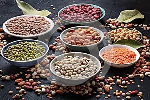 Legumes assortment on a black background. Lentils, soybeans, chickpeas, red kidney beans