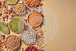 Legumes assortment, shot from above on a rustic brown background with copy space. Lentils, soybeans, chickpeas, red