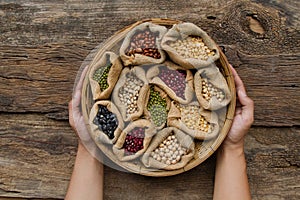 Legumes in wooden basket holding by hand