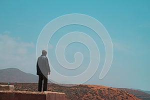 Legzira, Morocco - unrecognizable adult man stands contemplatively on the edge of a cliff with head down.