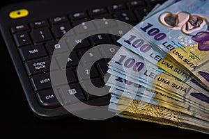 Lei banknotes on keyboard. Selective focus on stack of LEI romanian money