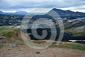 Leirhnjukur old black lava field with colorful stones  and blue sky in Iceland, overcast day in summer , film effect with grain