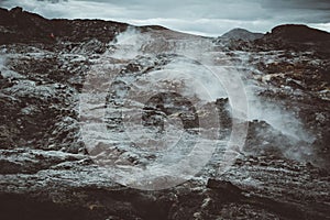 Leirhnjukur old black lava field with stones and smoke coming from ground in Iceland, overcast day in summer , film effect with