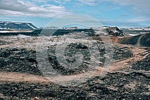 Leirhnjukur old black lava field with a tourist trail and blue sky in Iceland, overcast day in summer , film effect