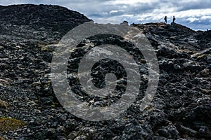 Leirhnjukur old black lava field and unrecognisable people on top in Iceland, overcast day in summer , film effect