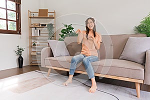 Leisure activities concept, Young woman in headphone listens music and dance while sitting on couch