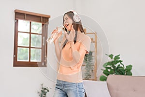 Leisure activities concept, Young woman wear headphone and hold water bottle to singing and dancing