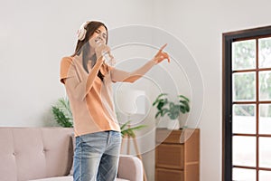 Leisure activities concept, Young woman wear headphone and hold water bottle to singing and dancing