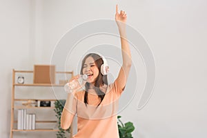 Leisure activities concept, Young woman wear headphone and hold water bottle to singing and dancing