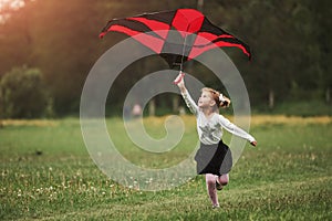Leisure activity. Happy girl in casual clothes running with kite in the field. Beautiful nature