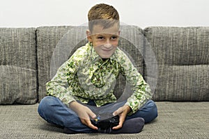 Leisure, children, technology and people concept - smiling boy with joystick playing video game at home