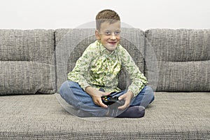 Leisure, children, technology and people concept - smiling boy with joystick playing video game at home