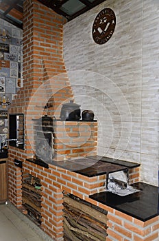 A corner made with exposed brick with barbecue, oven and wood stove photo