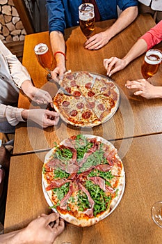 friends eating pizza with beer at restaurant